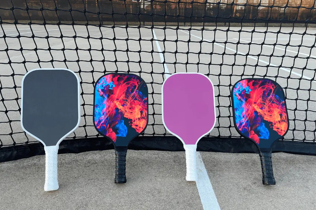 Pickleball paddles leaning against a net on a pickleball court